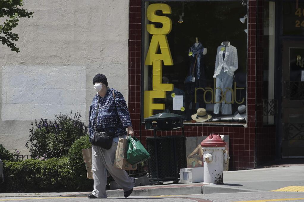 A woman wears a face mask while carrying shopping bags during the coronavirus outbreak in San Francisco, Thursday, May 7, 2020. California Gov. Gavin Newsom is preparing to loosen the state's stay-at-home order to allow some businesses to reopen as early as Friday. Newsom is scheduled to reveal new guidelines Thursday that could allow reopening of some retail outlets, including clothing shops, bookstores and florists, but they must heed social distancing rules. (AP Photo/Jeff Chiu)