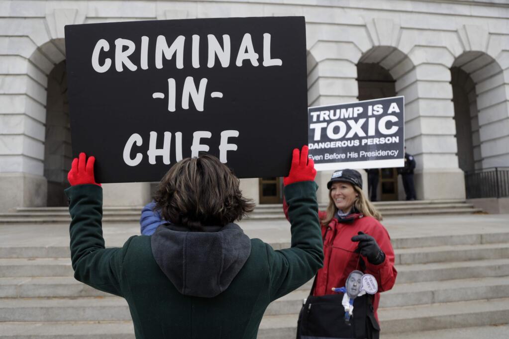 Demonstrators hold signs outside Longworth House Office Building, where U.S. Ambassador to the European Union Gordon Sondland is testifying before the House Intelligence Committee on Capitol Hill in Washington, Wednesday, Nov. 20, 2019, during a public impeachment hearing of President Donald Trump's efforts to tie U.S. aid for Ukraine to investigations of his political opponents. (AP Photo/Julio Cortez)