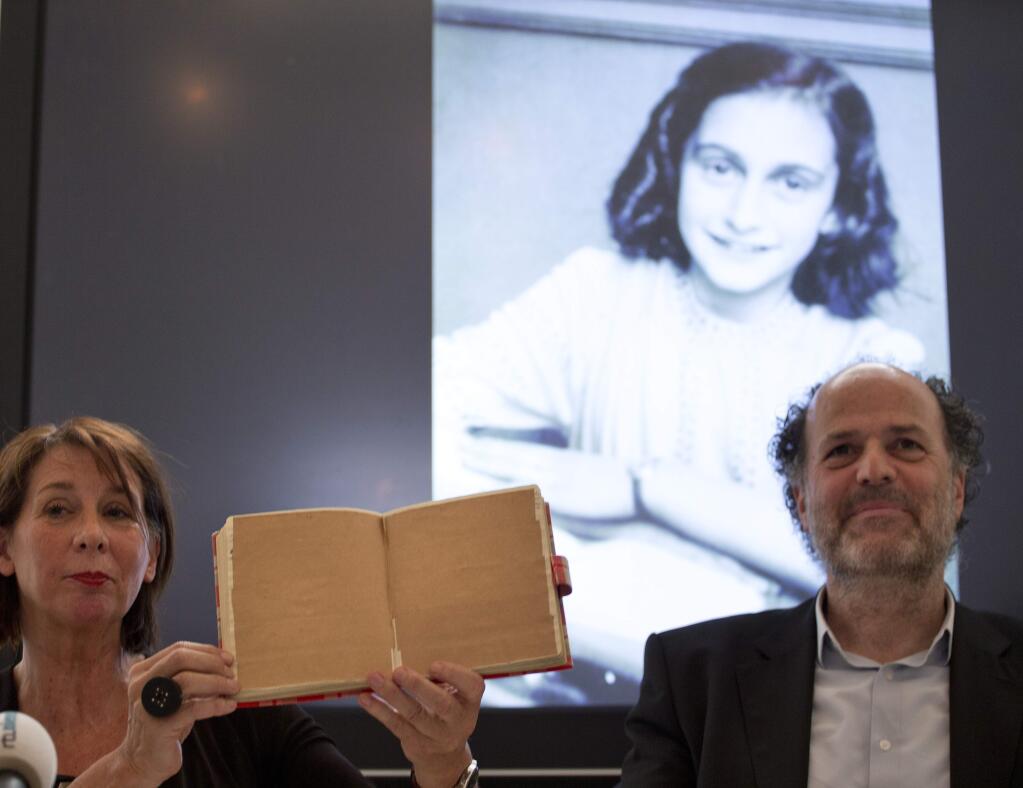 Teresien da Silva, left, and Ronald Leopold of the Anne Frank Foundation show a facsimile of Anne Frank's diary with two pages taped off during a press conference at the foundation's office in Amsterdam, Netherlands, Tuesday, May 15, 2018. Researchers have used digital photo editing techniques to uncover the text on two pages from Anne Frank's world famous diary that the teenage Jewish diarist had covered with brown masking paper, revealing risque jokes and an explanation of sex and prostitution. (AP Photo/Peter Dejong)