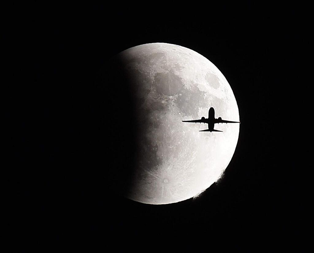 A plane flies in front of the so-called supermoon during a lunar eclipse Sunday, Sept 27, 2015 in Geneva, Ill. (Jeff Knox/Daily Herald via AP)