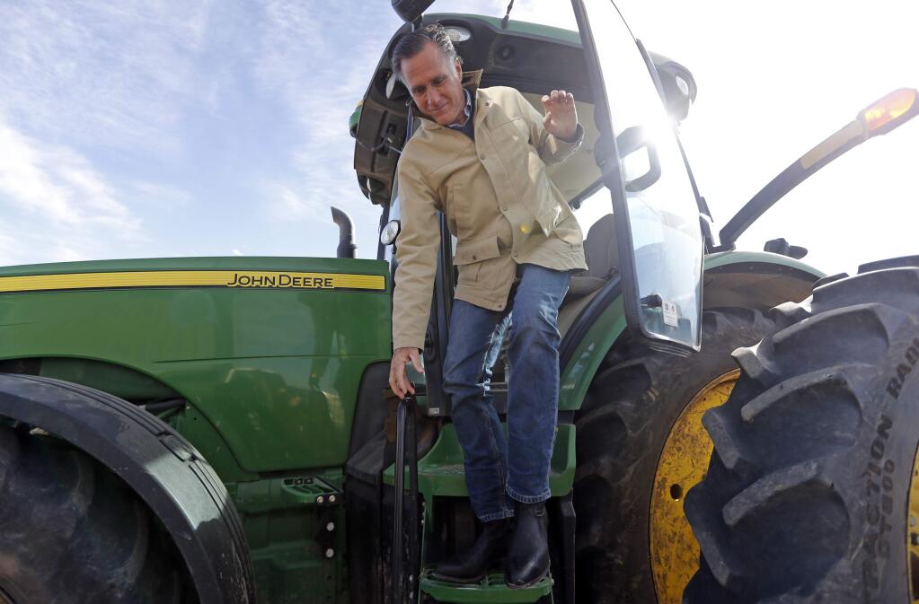Former Republican presidential candidate Mitt Romney climbs down from a tractor during a tour of Gibson's Green Acres Dairy Friday, Feb. 16, 2018, in Ogden, Utah. The 2012 Republican presidential candidate plans to bid for the seat being vacated by retiring seven-term Utah Sen. Orrin Hatch. (AP Photo/Rick Bowmer)