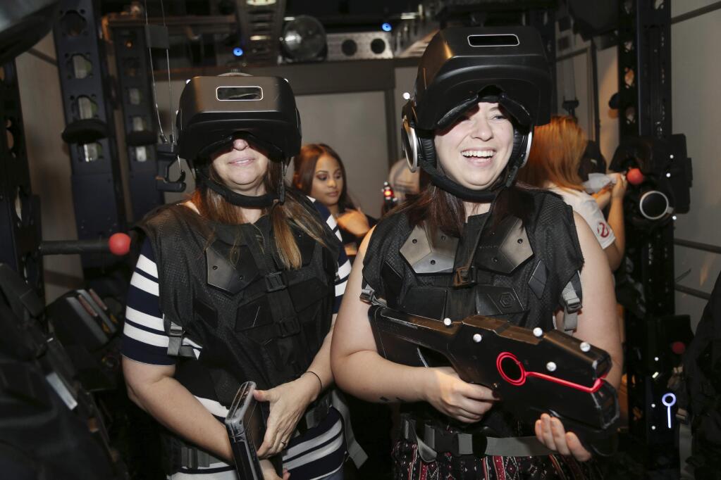 Marisa Ferrito, right, and her mother Michele Ferrito prepare to enter a virtual reality experience called 'Ghostbusters: Dimension' at Madame Tussauds in New York, Aug. 4, 2016. People who are curious about virtual reality but don't want to plunk down $1,000 or more on hardware are increasingly getting the chance to test out the medium for a price. From roller coaster rides to baseball games, VR can bring a new level of reality or simply detract from it. (AP Photo/Seth Wenig)
