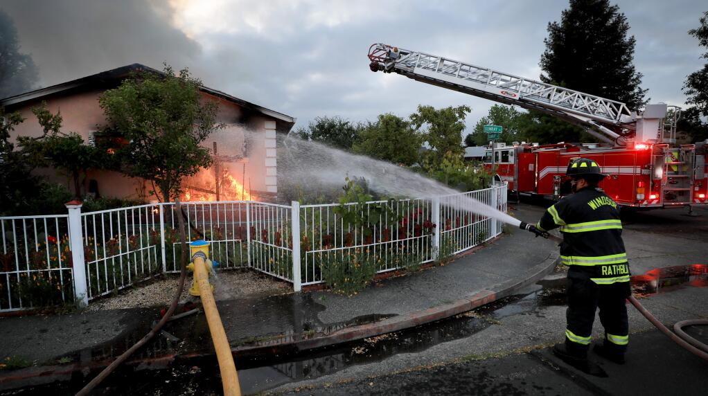 Sonoma County Fire District firefighter Tom Rathbun help fight a house fire on Sunray Place in Windsor, Tuesday, April 30, 2019. (Kent Porter / The Press Democrat) 2019