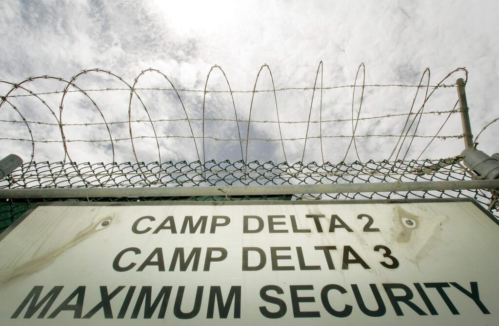 File - In this image reviewed by the U.S. Military, a razor-wired fence is shown above the Camp Delta 2 and 3 base sign, in this June 25, 2005 file photo taken at Guantanamo Bay Naval Base, Cuba. Aiming to break through congressional opposition to White House plans to shutter the detention facility at Guantanamo Bay, Cuba, a group of retired generals and war veterans have launched the 'Close Gitmo Now' campaign, that includes a relatively modest $100,000 ad buy on cable channels Wednesday Oct. 21, 2009, its message exhorting Congress to reject the 'failed Bush-Cheney policies.' to rally support for closing the prison. (AP Photo/Haraz Ghanbari, File)