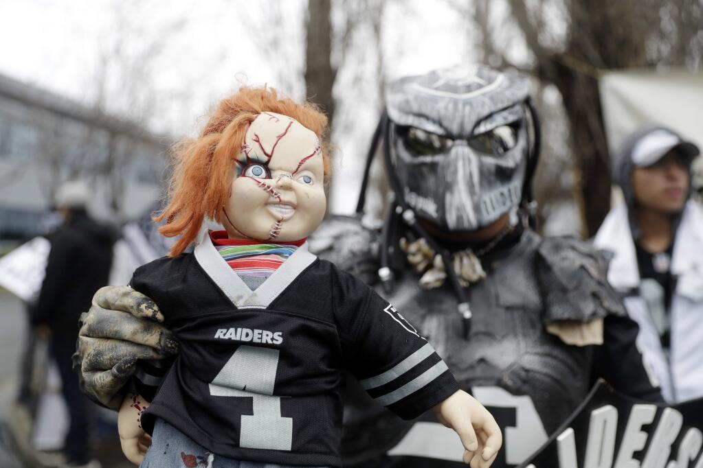 A fans holds a Chucky doll outside of the Oakland Raiders team headquarters before a press conference to announce John Gruden as the team's new coach Tuesday, Jan. 9, 2018, in Alameda. (AP Photo/Marcio Jose Sanchez)