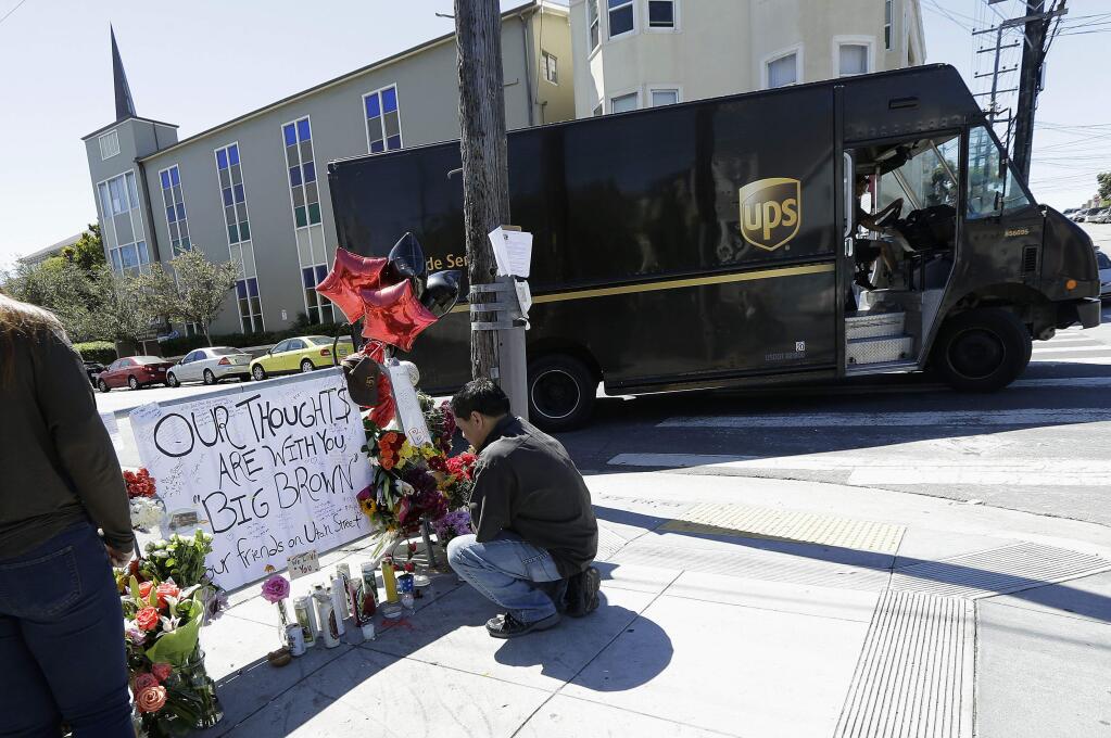 Sherwin Karunungan, a friend of Benson Louie and Wayne Chan, two of the UPS drivers slain on Wednesday, kneels down in front of a memorial set up outside of the UPS facility in San Francisco, Friday, June 16, 2017. Police say the three UPS drivers were killed by 38-year-old Jimmy Lam, who fatally shot himself in the head in front of officers. (AP Photo/Jeff Chiu)