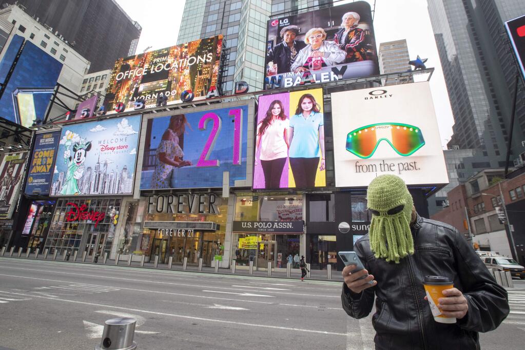 Jon Makay, of Harlem, wears an octopus hat to fend off coronavirus, Wednesday, March 25, 2020, in New York's Times Square. The number of people hospitalized with COVID-19 in New York climbed to 3,800, with close to 900 in intensive care, with the peak of the outbreak weeks away, Gov. Andrew Cuomo said Wednesday. The new coronavirus causes mild or moderate symptoms for most people, but for some, especially older adults and people with existing health problems, it can cause more severe illness or death. (AP Photo/Mary Altaffer)