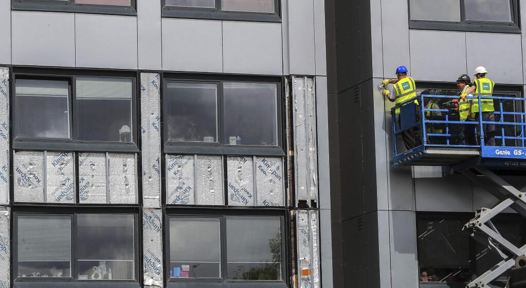 Workers remove cladding from Whitebeam Court, in Pendleton, Manchester, Monday June 26, 2017. The list of high-rise apartment towers in Britain that have failed fire safety tests grew to 60, officials said Sunday, revealing the mounting challenge the government faces in the aftermath of London's Grenfell Tower fire tragedy. (Peter Byrne/PA via AP)