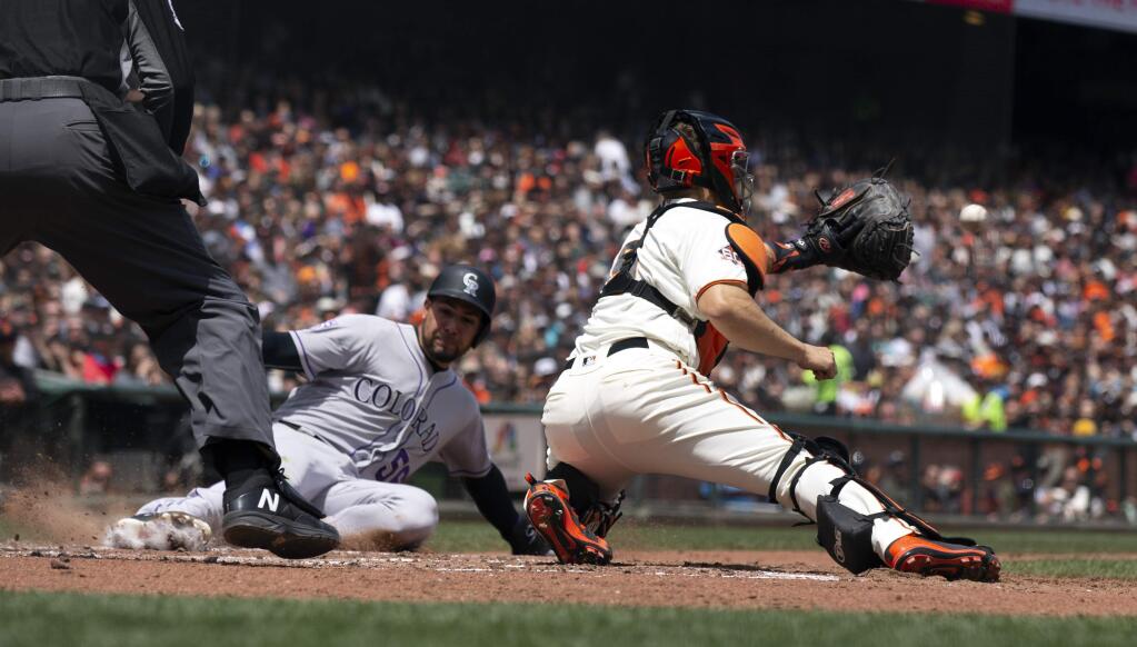 San Francisco Giants catcher Nick Hundley, right, prepares to put the tag on Colorado Rockies Noel Cuevas (56) who was trying to score on a double by Pat Valaika during the fourth inning of a baseball game, Sunday, May 20, 2018, in San Francisco. (AP Photo/D. Ross Cameron)