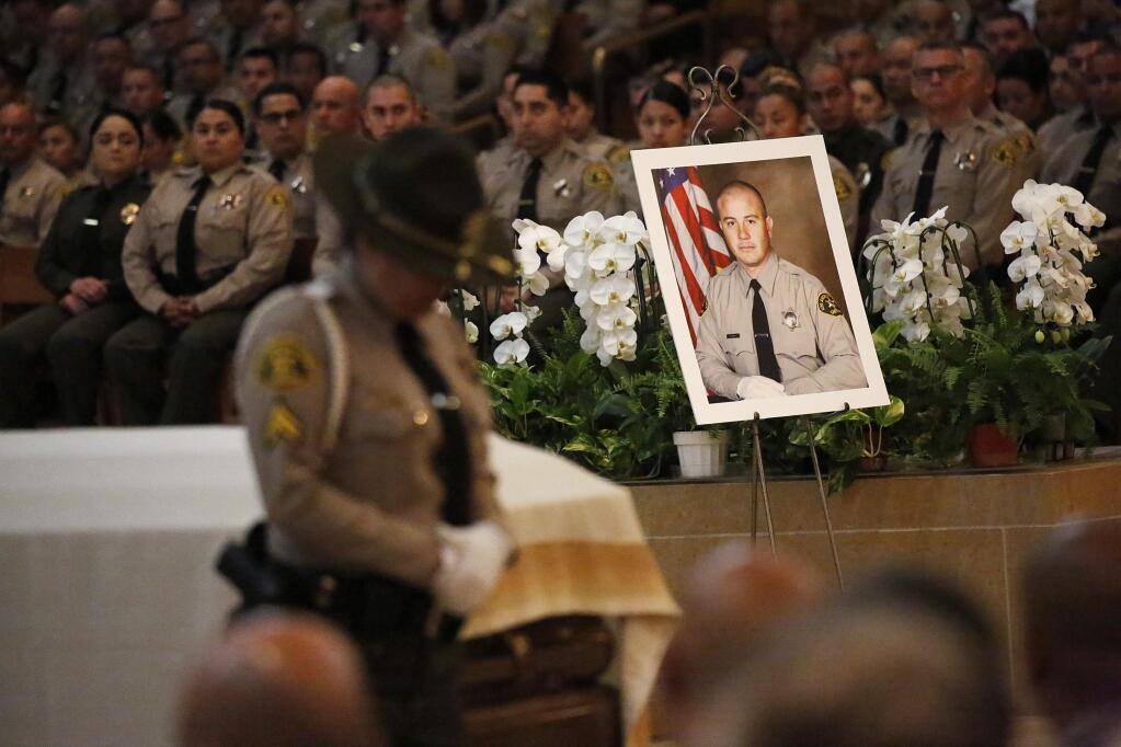 A portrait sits next to the casket of Los Angeles County Sheriff's Deputy Joseph Solano during a memorial service Monday morning, June 24, 2019, at Cathedral of Our Lady of the Angels in Los Angeles. Solano, shot in an off-duty attack, was remembered Monday as an inspiration to his family and colleagues for his positive attitude and devotion to public service. (Al Seib/Los Angeles Times via AP, Pool)