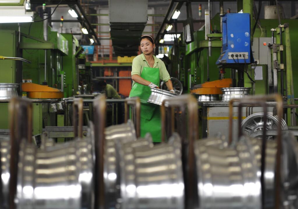 FILE - In this Thursday, Aug. 21, 2014 file photo, a woman works at a factory manufacture aluminum wheel hubs in Zouping county in east China's Shandong province. In 2014, China's growth dropped to a five-year low of 7.3 percent, and manufacturing is skidding. (AP Photo/File) CHINA OUT