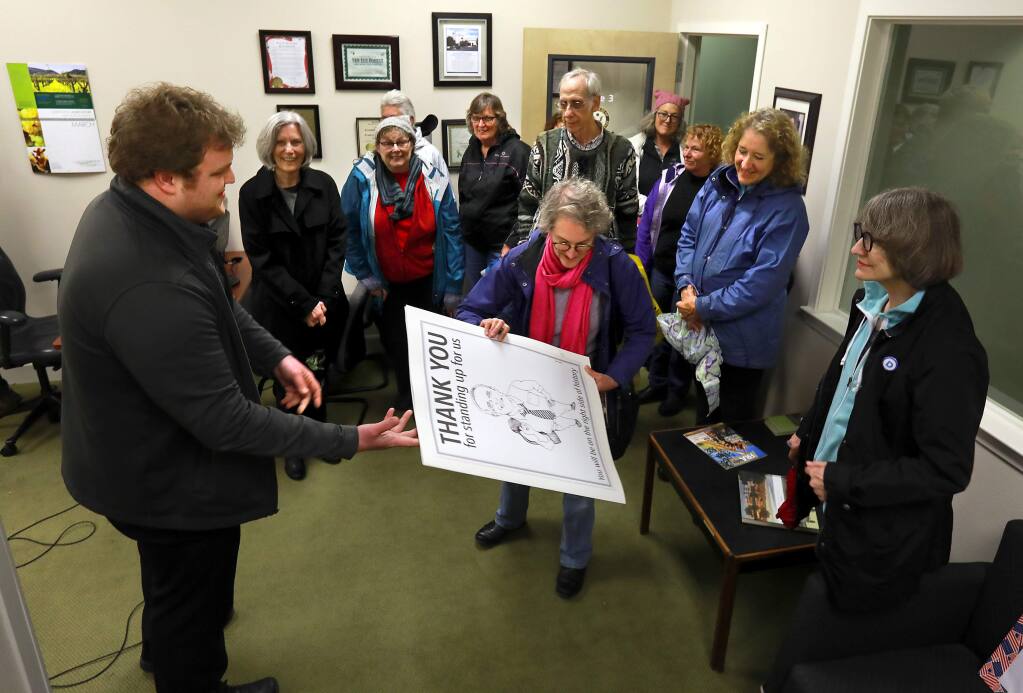 A dozen people presented U.S. House Representative Jared Huffman's field representative Blake Hooper with a poster thanking him for his opposition to the proposed American Health Care Act. (John Burgess/The Press Democrat)