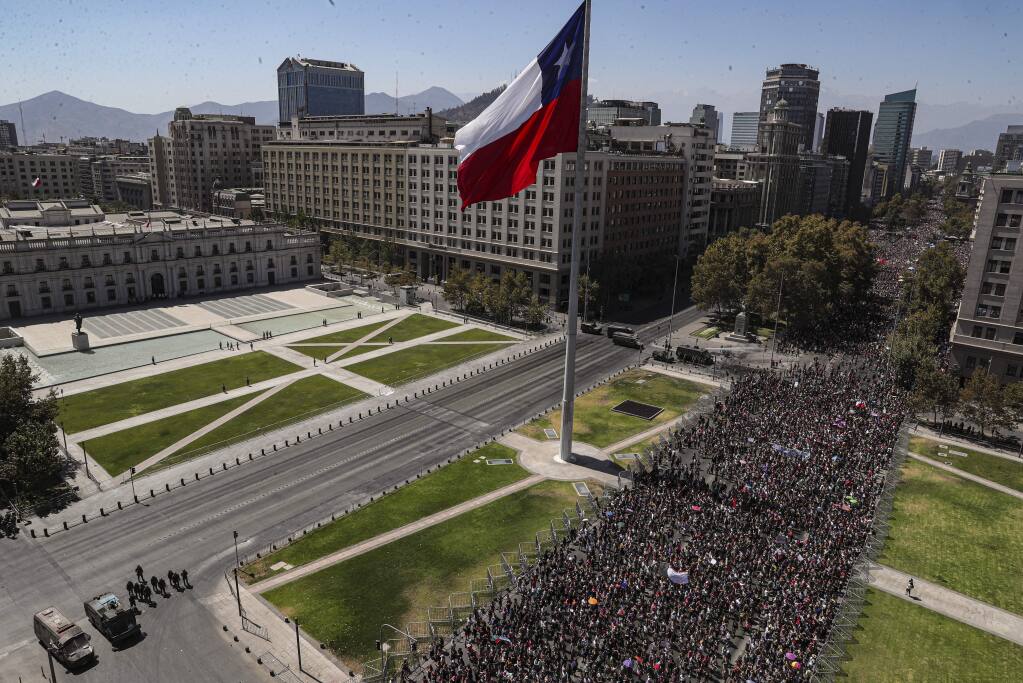 Women gather near La Moneda presidential palace during a march marking International Women's Day, in Santiago, Chile, Sunday, March 8, 2020. (AP Photo/Esteban Felix)