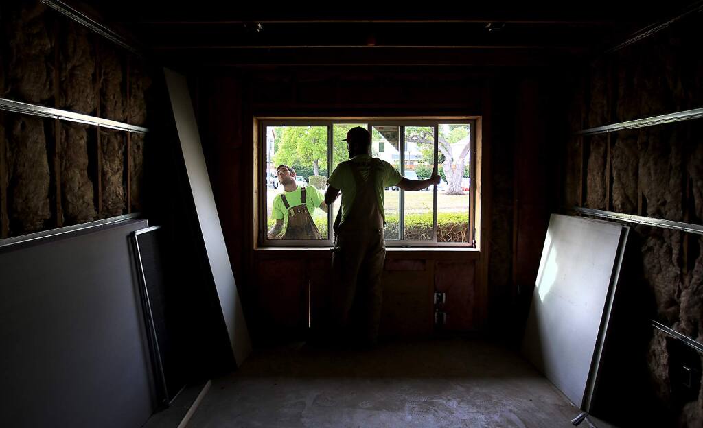Redhawk Glass apprentices Kyle Goff, left and Galen Isadore fit a window in client room at the SAY Dream Center, Friday Aug. 28, 2015. (Kent Porter / Press Democrat) 2015