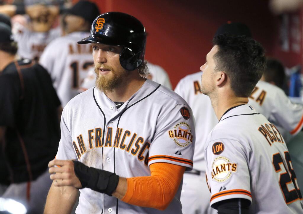 San Francisco Giants' Hunter Pence, left, walks past teammate Buster Posey, right, after Pence scored a run against the Arizona Diamondbacks during the second inning of a baseball game Friday, July 17, 2015, in Phoenix. (AP Photo/Ross D. Franklin)