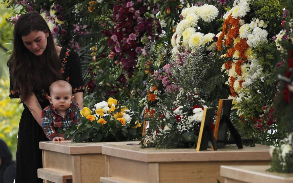 A woman and child stand by the coffins of Dawna Ray Langford, 43, and her sons Trevor, 11, and Rogan, 2, who were killed by drug cartel gunmen, during the funeral at a family cemetery in La Mora, Sonora state, Mexico, Thursday, Nov. 7, 2019. Three women and six of their children, all members of the extended LeBaron family, died when they were gunned down in an attack while traveling along Mexico's Chihuahua and Sonora state border on Monday. (AP Photo/Marco Ugarte)