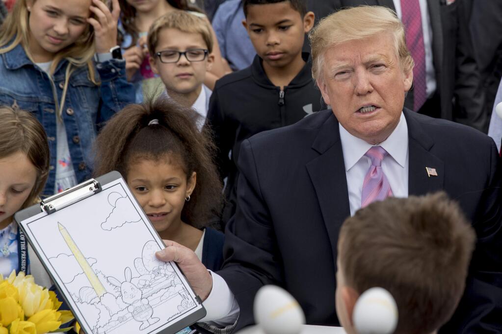 President Donald Trump shows a drawing of the Washington Monument he colored in as he sits with children during the annual White House Easter Egg Roll on the South Lawn of the White House, Monday, April 22, 2019, in Washington. (AP Photo/Andrew Harnik)