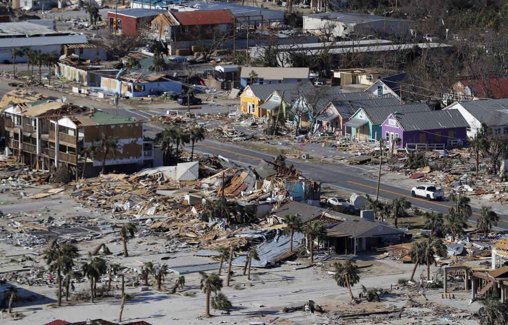 FILE - This Oct. 12, 2018 aerial file photo shows devastation from Hurricane Michael over Mexico Beach, Fla. A massive new federal report warns that extreme weather disasters, like California‚Äôs wildfires and 2018‚Äôs hurricanes, are worsening in the United States. The White House report quietly issued Friday, Nov. 23 also frequently contradicts President Donald Trump. (AP Photo/Gerald Herbert, File)