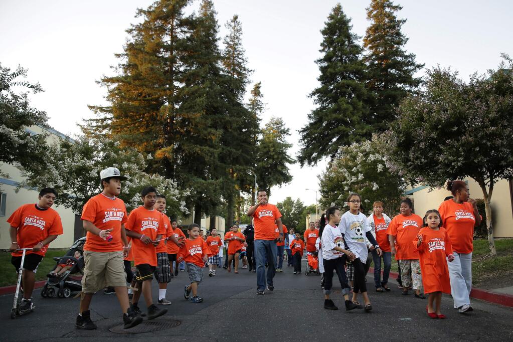Young residents of the Puerta Villa Apartment along West 9th Street get ready to walk through their neighborhood during a community walk led by police officers and community organizers in Santa Rosa on Friday, Aug. 8, 2014. (Conner Jay/The Press Democrat)