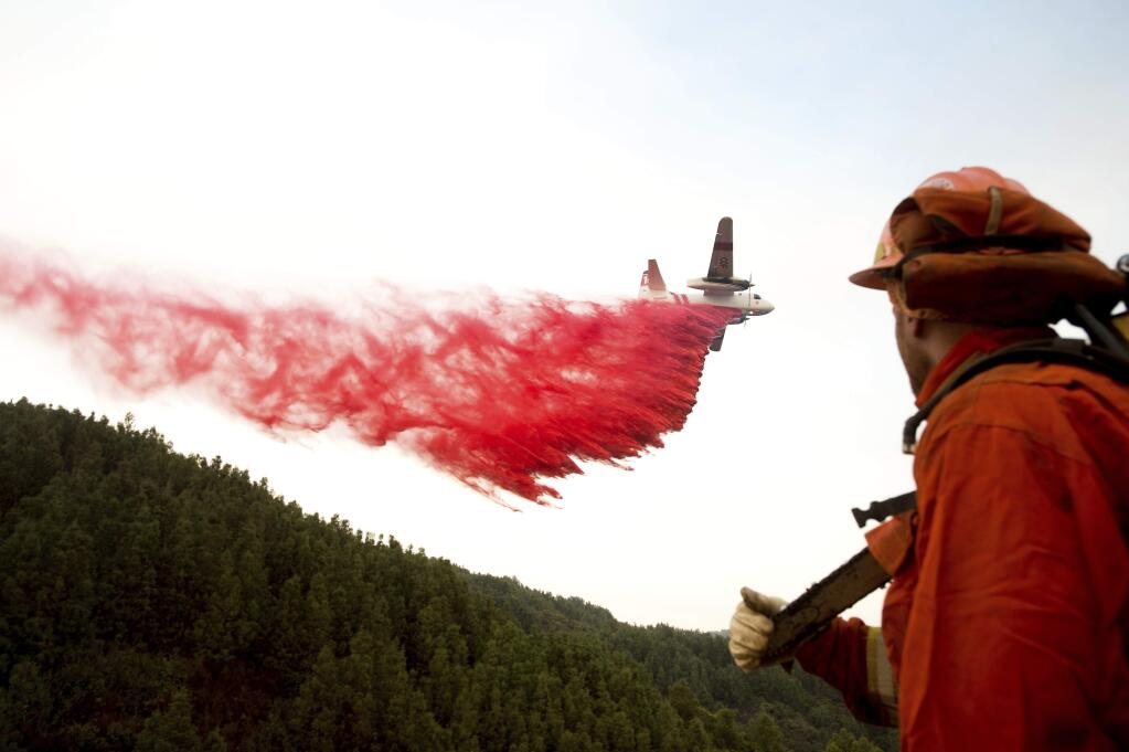 FILE--In this Sept. 28, 2016, file photo, an inmate firefighter watches as an air tanker drops retardant while battling a wildfire near Morgan Hill, Calif. Forecasters say Hawaii and pockets of the Southeastern and Southwestern United States could face above-normal danger of significant wildfires this summer.(AP Photo/Noah Berger, file)