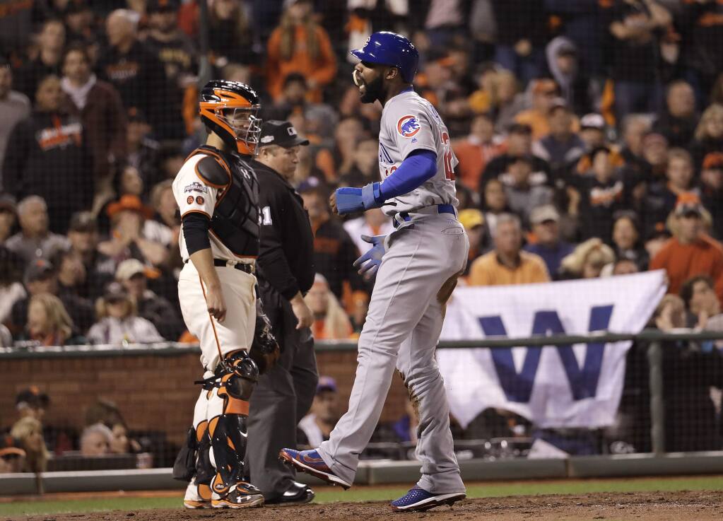 Chicago Cubs' Jason Heyward, right, reacts next to San Francisco Giants catcher Buster Posey after scoring during the ninth inning of Game 4 of baseball's National League Division Series in San Francisco, Tuesday, Oct. 11, 2016. (AP Photo/Marcio Jose Sanchez)