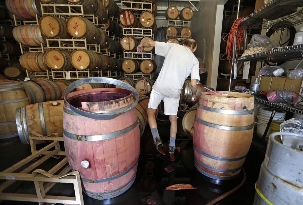 Winemaker Tom Montgomery walks through wine to see the damage following an earthquake at the B.R. Cohn Winery barrel storage facility Sunday, Aug. 24, 2014, in Napa, Calif. (AP Photo/Eric Risberg)