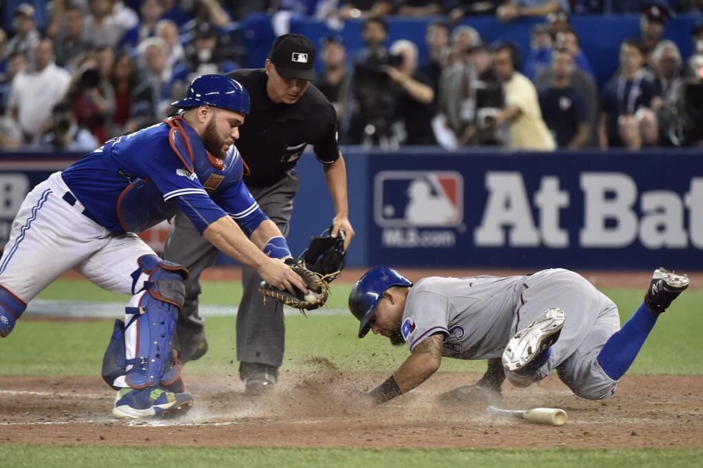 Toronto Blue Jays' catcher Russell Martin, left, attempts to tag Texas Rangers' Rougned Odor, right, who scores during the 14th inning of Game 2 of the American League Division Series in Toronto, Friday, Oct. 9, 2015. (Nathan Denette/The Canadian Press via AP) MANDATORY CREDIT
