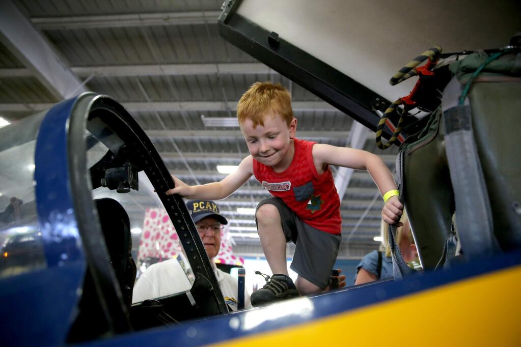 Mason Stoneburner, 4, climbs into the cockpit of a Blue Angel trainer from the Pacific Coast Air Museum during the Ride-A-Rig event hosted by the Junior League of Napa-Sonoma at the Sonoma County Fairgrounds in Santa Rosa on Sunday, June 23, 2019. (BETH SCHLANKER/ The Press Democrat)