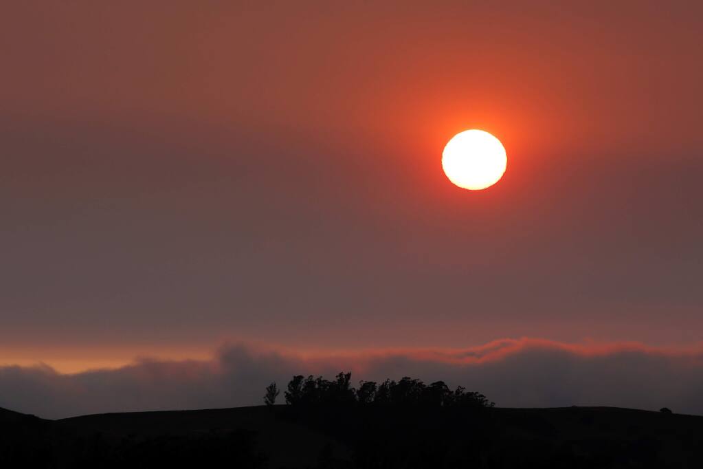 The sun begins to set behind layers of haze, a result of the recent northern California wildfires, above the hills west of Petaluma, California, on Wednesday, Aug. 8, 2018. (ALVIN JORNADA/ PD)