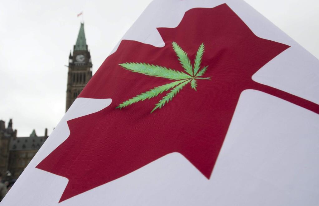 FILE - In this April 20, 2015 file photo, a Canadian flag with a cannabis leaf flies on Parliament Hill during a 4/20 protest in Ottawa, Ontario. Canada is following the lead of Uruguay in allowing a nationwide, legal marijuana market, although each Canadian province is working up its own rules for pot sales. The federal government and the provinces also still need to publish regulations that will govern the cannabis trade. (Adrian Wyld/The Canadian Press via AP, File)