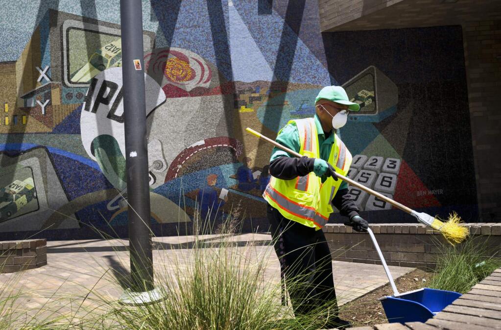 A cleaning crew sweeps up in front of LAPD Central Community Police Station in downtown Los Angeles on Thursday, May 30, 2019. The union that represents the LAPD is demanding a cleanup of homeless encampments in the city after one detective who works downtown was diagnosed with typhoid fever and two others are showing similar symptoms. (AP Photo/Richard Vogel)