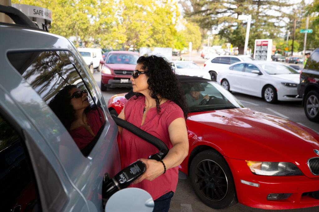 Deborah Arnett of Santa Rosa pumps gas into her SUV, as she and other motorists top off their gas tanks in preparation for the PG&E outage at the Safeway gas station in Santa Rosa on Tuesday, Oct. 8, 2019. (Alvin Jornada / The Press Democrat)