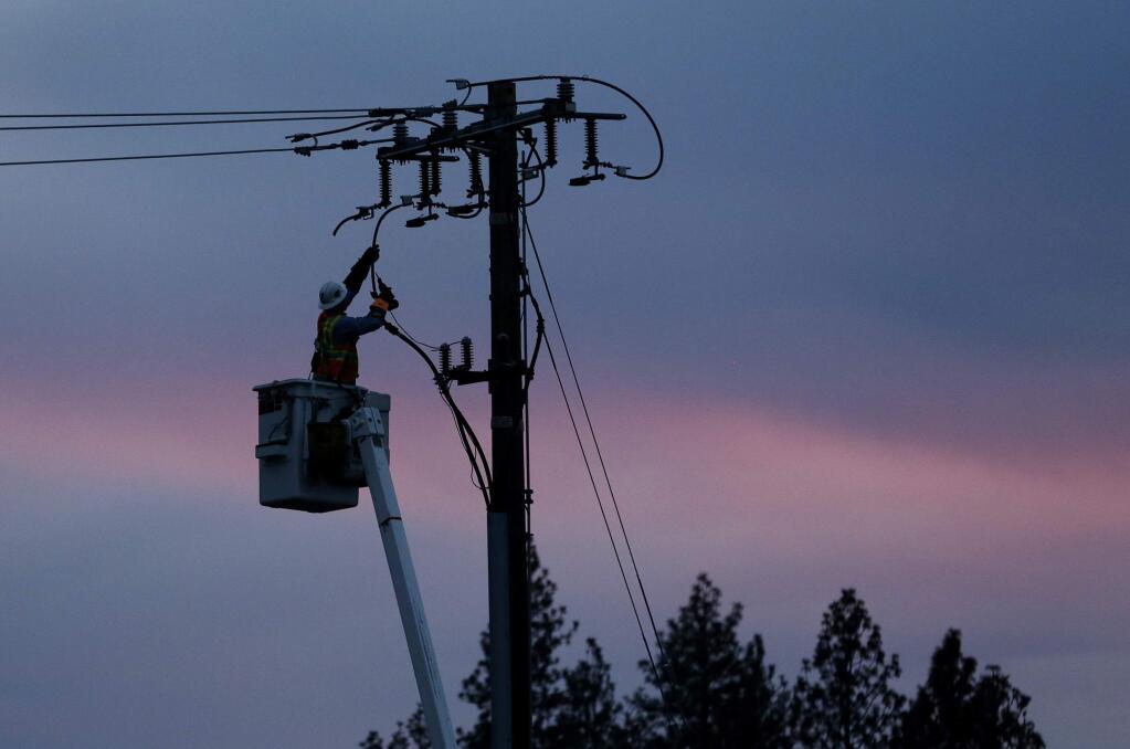 FILE - In this Nov. 26, 2018, file photo, a Pacific Gas & Electric lineman works to repair a power line in fire-ravaged Paradise, Calif. A last-minute change to a bill meant to stabilize California's electric utilities could also make it harder for local governments to buy pieces of power companies' assets and run their electric services. Critics say the change, which would provide protections for workers in case of ownership changes, could potentially make it harder for cities to buy PG&E assets. (AP Photo/Rich Pedroncelli, File)