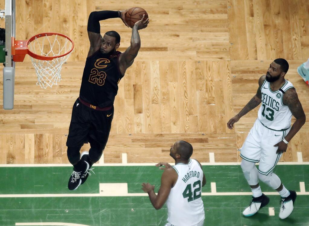 Cleveland Cavaliers forward LeBron James soars to dunk in front of Boston Celtics forward Al Horford (42) and forward Marcus Morris (13) during the first half in Game 7 of the NBA basketball Eastern Conference finals, Sunday, May 27, 2018, in Boston. (AP Photo/Charles Krupa)