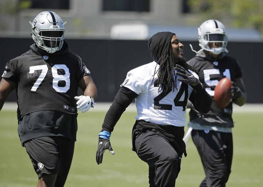 Oakland Raiders running back Marshawn Lynch (24) stretches with defensive tackle Justin Ellis (78) and linebacker Bruce Irvin (51) during workouts Tuesday, May 23, 2017, in Alameda. (AP Photo/Eric Risberg)