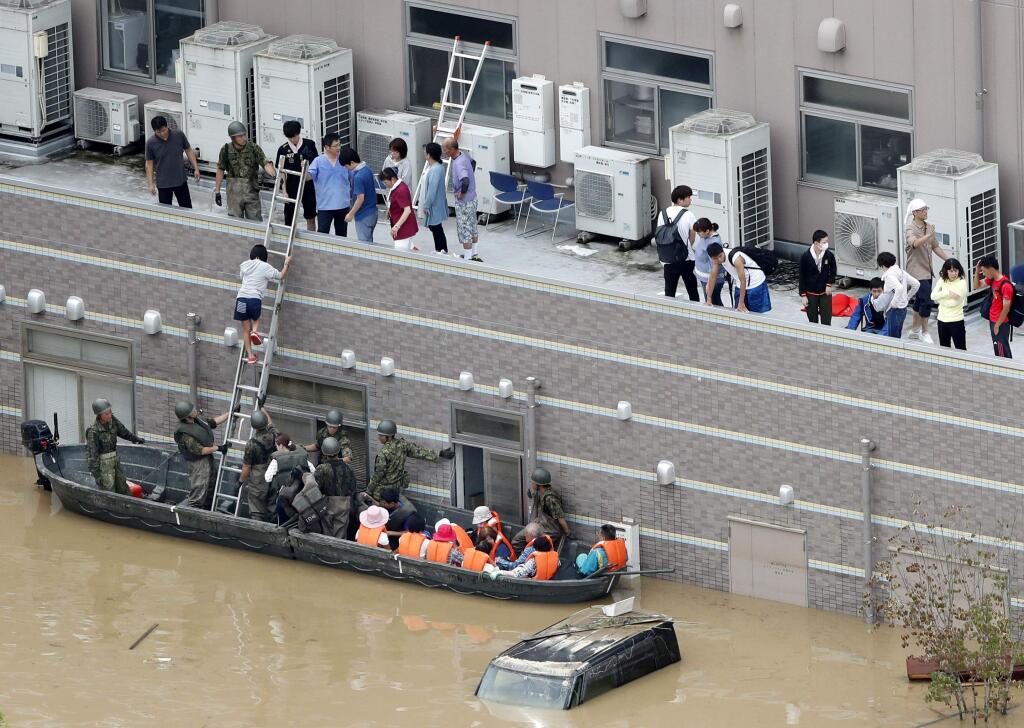 People who are stranded at a flooded hospital are rescued following heavy rain in Kurashiki city, Okayama prefecture, southwestern Japan, Sunday, July 8, 2018. Heavy rainfall hammered southern Japan for the third day, prompting new disaster warnings on Kyushu and Shikoku islands on Sunday. (Shohei Miyano/Kyodo News via AP)