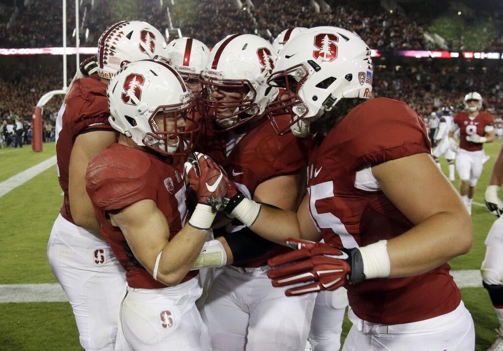 Stanford's Christian McCaffrey, left, is mobbed by teammates after his touchdown run against Arizona during the first half of an NCAA college football game Saturday, Oct. 3, 2015, in Stanford, Calif. (AP Photo/Marcio Jose Sanchez)