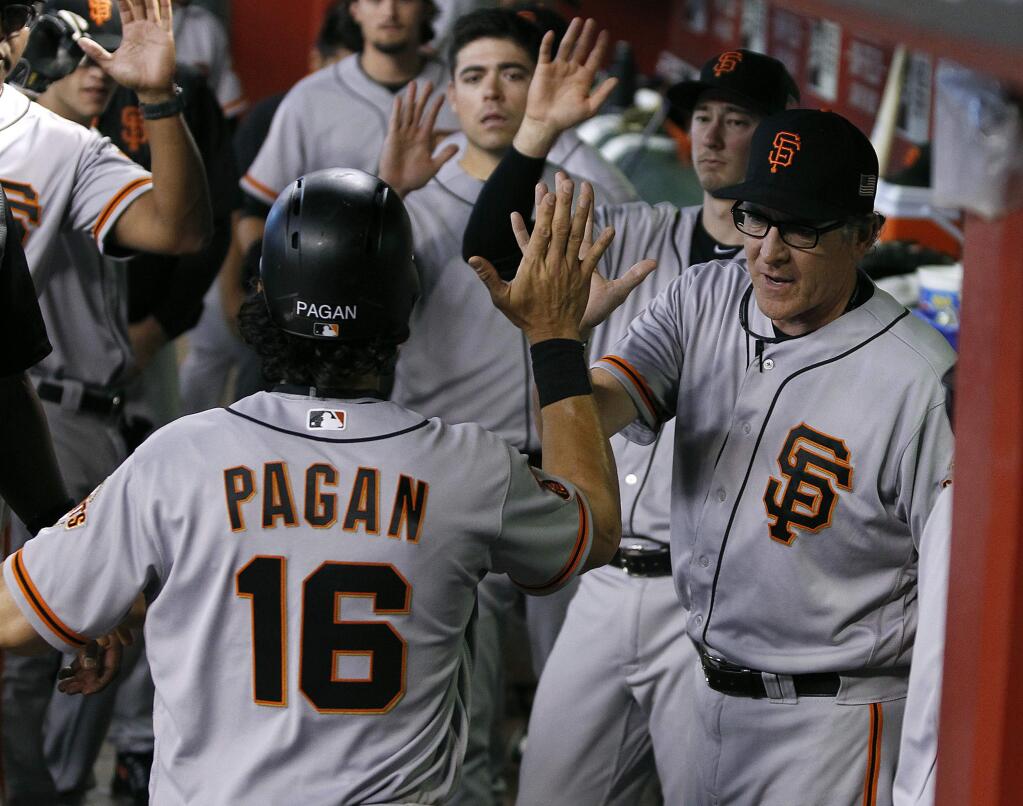 San Francisco Giants' Angel Pagan (16) is congratulated by pitching coach Dave Righetti, right, and teammates after scoring against the Arizona Diamondbacks during the sixth inning of a baseball game, Sunday, Sept. 11, 2016, in Phoenix. (AP Photo/Ralph Freso)