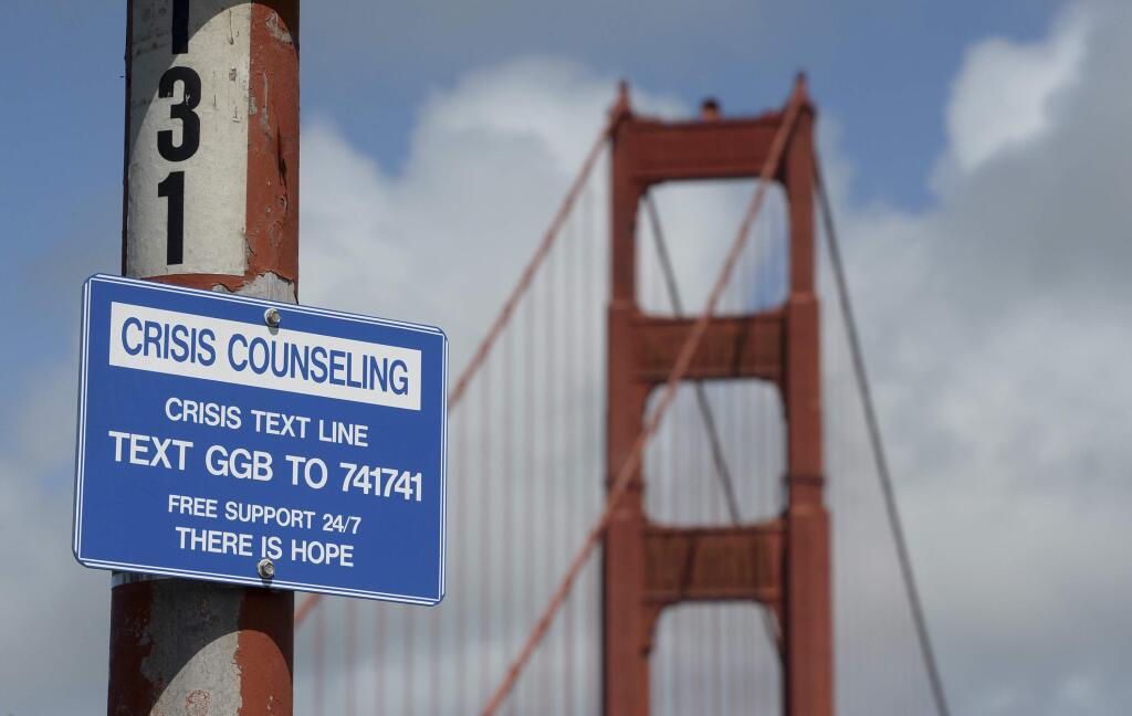 A suicide prevention sign is posted at the Golden Gate Bridge, Thursday, April 13, 2017, in San Francisco. Local officials gathered Thursday at the orange-red span to mark the beginning of work to line both sides of the bridge with steel netting. (Alan Dep/Marin Independent Journal via AP)