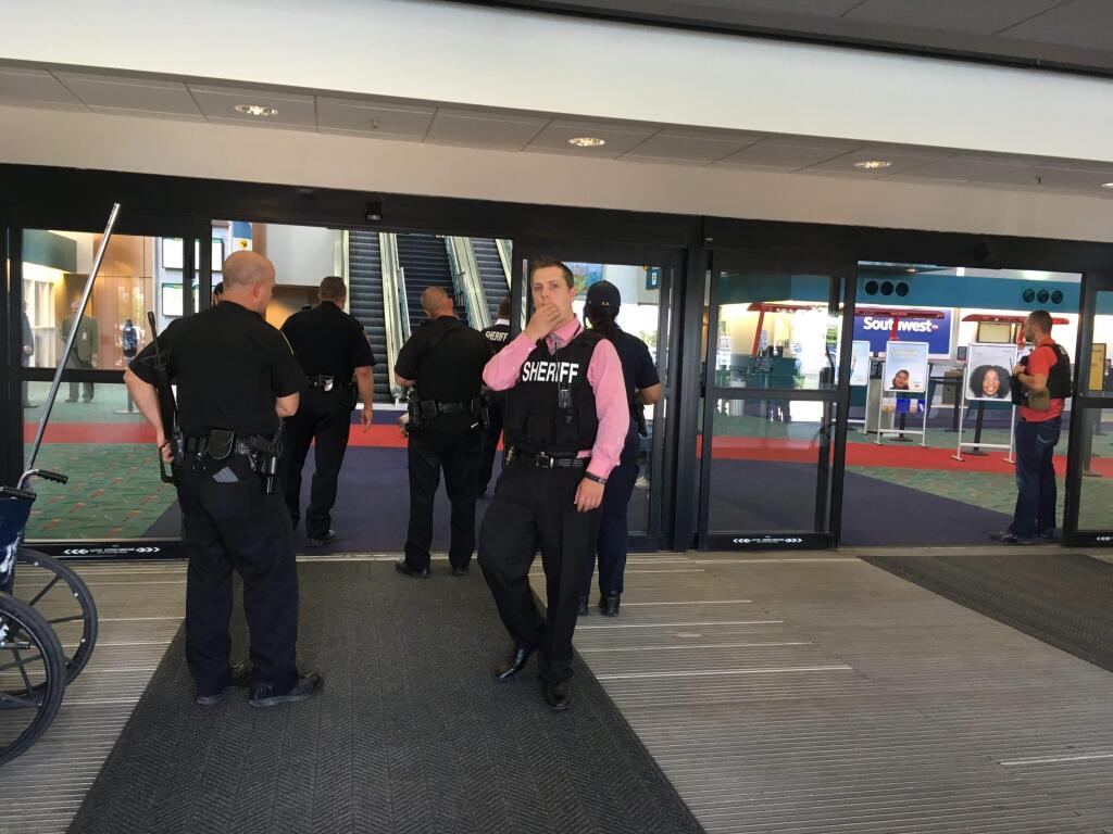 Police officers gather at a terminal at Bishop International Airport, Wednesday morning, June 21, 2017, in Flint, Mich. Officials evacuated the airport Wednesday, where a witness said he saw an officer bleeding from his neck and a knife nearby on the ground. On Twitter, Michigan State Police say the officer is in critical condition and the FBI was leading the investigation. (Dominic Adams/The Flint Journal-MLive.com via AP)