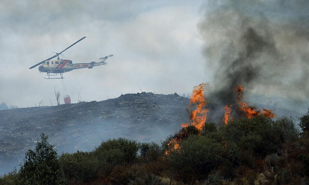 A water dropping helicopter heads back to get more water as a wildfire burns near homes in the brush in Beaumont, Calif., Tuesday, Aug. 30, 2016. (Terry Pierson/The Press-Enterprise via AP)