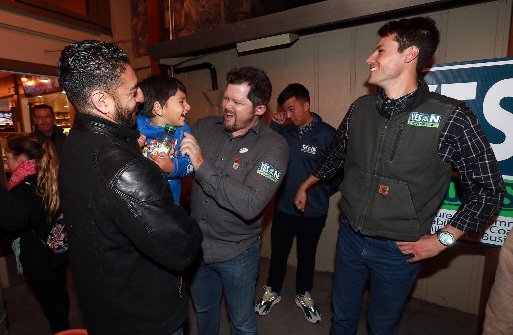 From left, former County Supervisor Efren Carrillo and his son Maximiliano laugh with housing advocate Chris Grabill and Santa Rosa City Council member Jack Tibbetts at a Yes on N election night party at Mountain Mike's Pizza in Santa Rosa. (John Burgess/The Press Democrat)