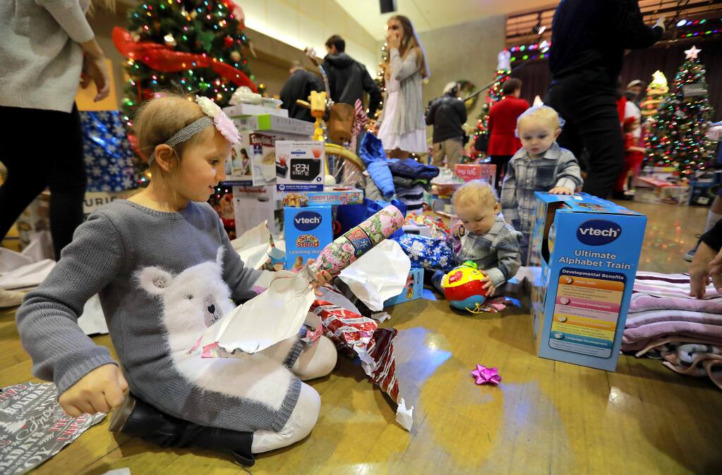 John Burgess / The Press DemocratKapri Geernaert, 9, and her twin brothers Kade and Kolton, 1, open the last of their presents at the Finley Center in Santa Rosa.