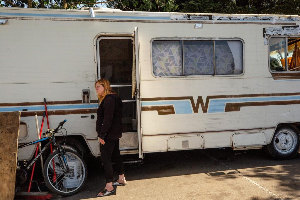 Melanie Dawson, 47, stands beside the door of the motor home where she lives, in a parking lot near the SMART train crossing at Golf Course Drive, in Rohnert Park, California, on Friday, July 19, 2019. (Alvin Jornada / The Press Democrat)