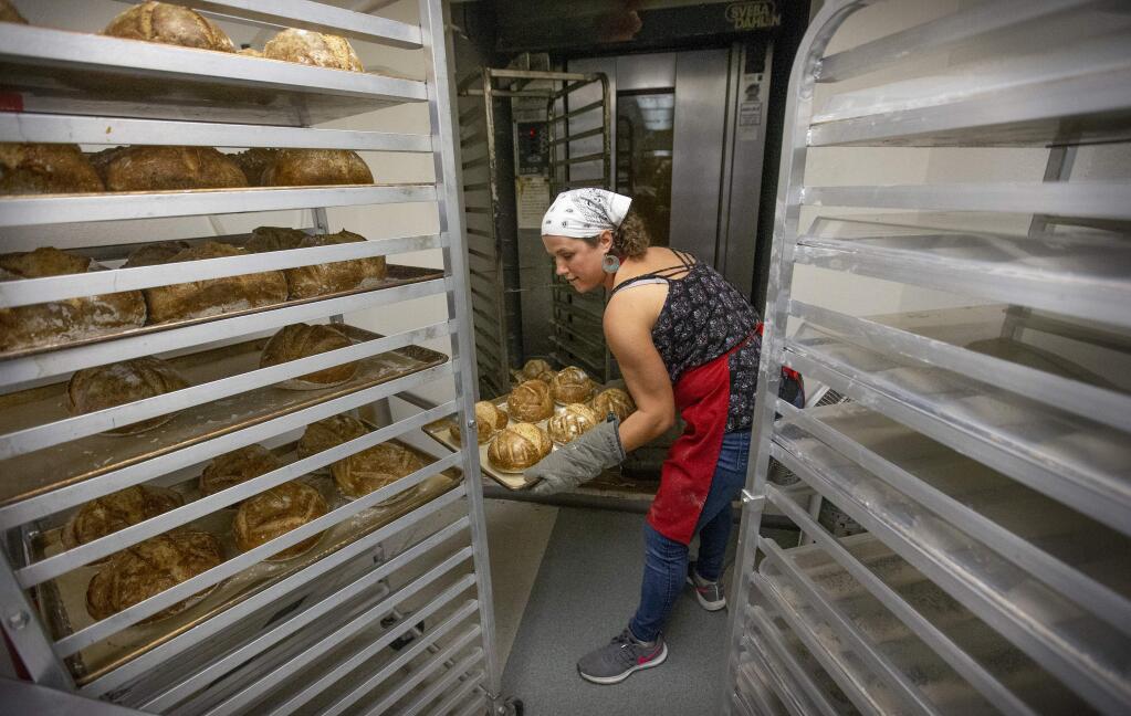 Mellisa Wentzel unloads fresh gluten-free wild flour sourdough levain loaves from the oven at Mama Mel's Bread in Petaluma. (photo by John Burgess/The Press Democrat)