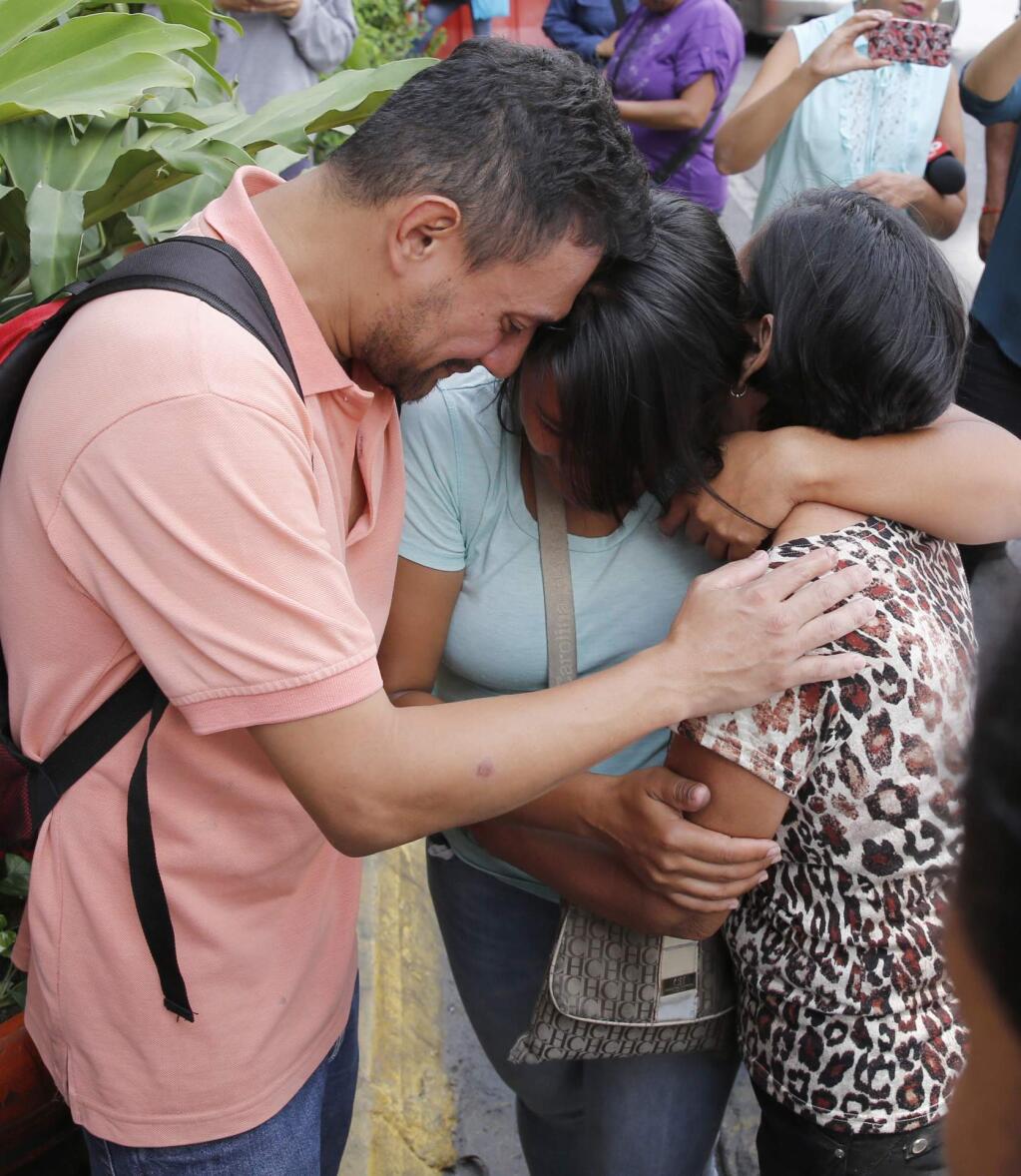 Barbara Barca, center, a survivor of the stampede at a crowded nightclub, is hugged by relatives as they leave police headquarters in Caracas, Venezuela, Saturday, June 16, 2018. Venezuela's government says 17 people were killed early Saturday after a tear gas device was set off during a nightclub brawl in the capital, leading hundreds of people to flee. (AP Photo/Ariana Cubillos)