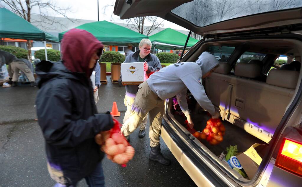The Redwood Empire Food Bank volunteers load food into cars on Wednesday during a special giveaway for fire victims. The Food Bank is spending about $200,000 more per month on the program. (photo by John Burgess/The Press Democrat)