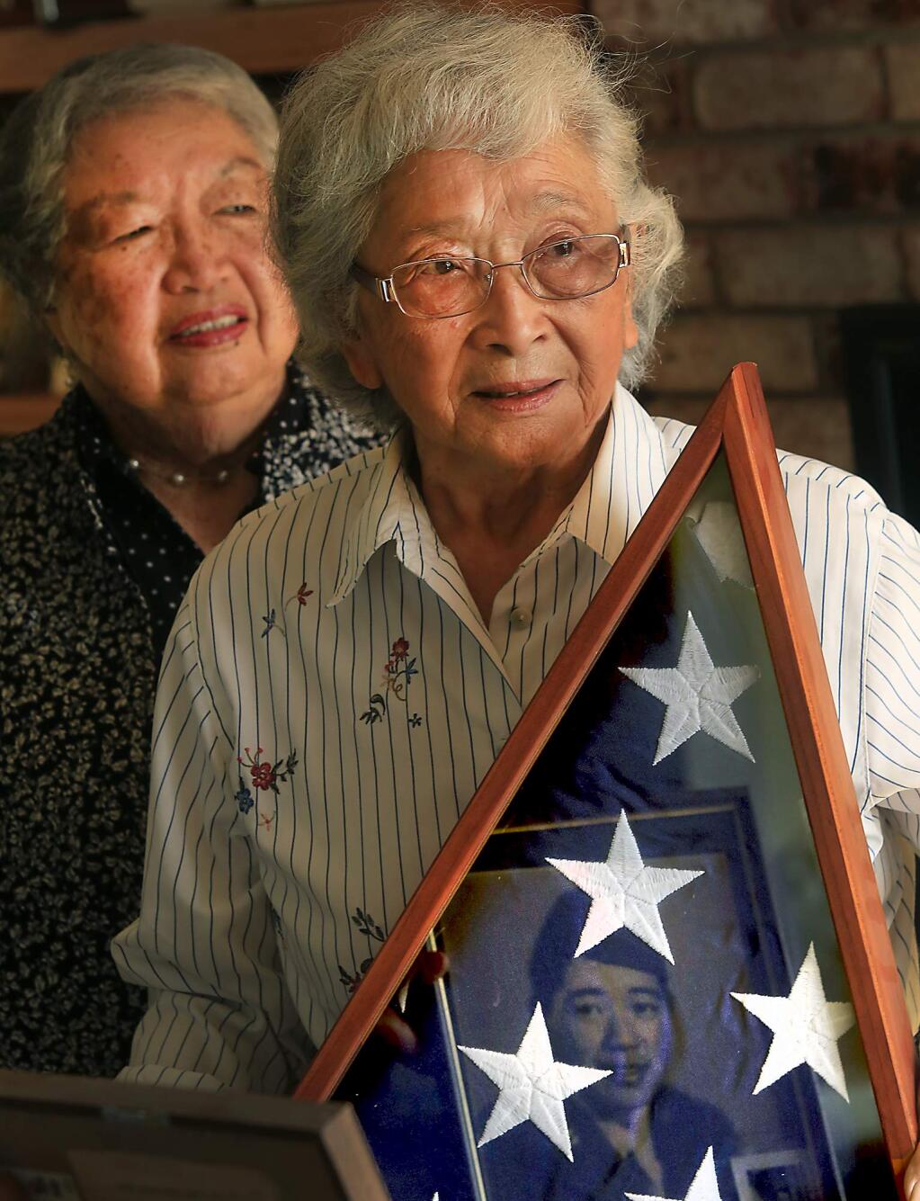 Marie Sugiyama, left and her sister-in-law Alyce Yamasaki Sugiyama with an American flag that belonged to her husband Harry Sugiyama who died in 2014. All three were in local World War II Japanese internment camps. Her husband was drafted out of the camp by the U.S. Armed Forces to fight in the war. (Kent Porter / Press Democrat) 2016