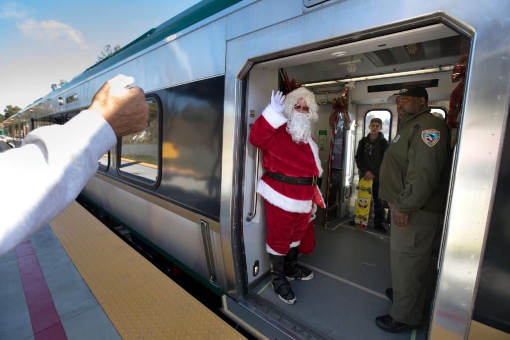 Santa Claus waves to passengers as the SMART train prepares to depart Larkspur north to Santa Rosa. (Darryl Bush / For The Press Democrat, 2019)