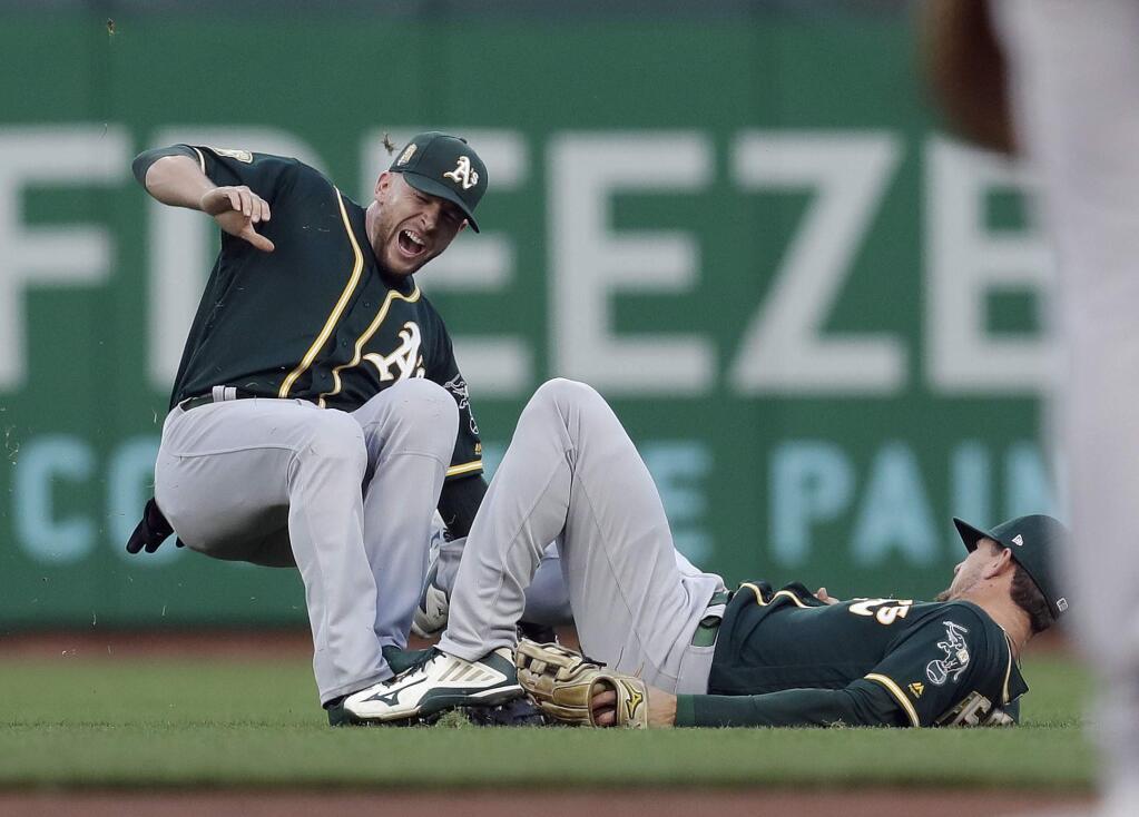 Oakland A's second baseman Jed Lowrie, left, collides with right fielder Stephen Piscotty after Lowrie caught a fly ball from the San Francisco Giants' Alen Hanson during the third inning Friday, July 13, 2018, in San Francisco. (AP Photo/Marcio Jose Sanchez)